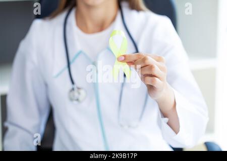 Femme en gros plan dans un t-shirt blanc tenant et montrant le ruban de conscience jaune dans ses mains Banque D'Images