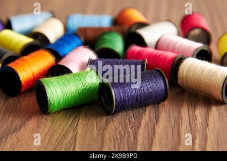 Tas de bobines de fils colorés sur la table en bois tailleur. Arrière-plans à motif brodé Banque D'Images