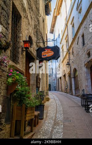 Charme rustique : une scène de rue typique dans la vieille ville de Spoleto avec des maisons traditionnelles en pierre et une ruelle étroite photographiée tôt le matin. Ombrie, Italie. Banque D'Images