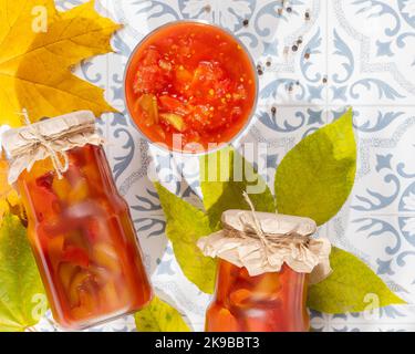 Aliments probiotiques. Légumes marinés ou fermentés. Lecho, piments doux en pots de verre sur une table en carreaux avec des ombres et des feuilles d'automne. Maquette de pré-alimentation Banque D'Images