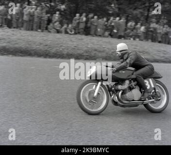 1954, le concurrent historique 31 sur son motovélo sur le circuit de course de Mount Road d'Oliver à Scarborough, sous la surveillance de spectateurs se tenant plus haut sur l'herbe surplombant la piste, Angleterre, Royaume-Uni. Le circuit vallonné du Mount Oliver est le seul circuit de course « routier » naturel d'Angleterre et, à cette époque, les courses de moto étaient connues sous le nom de courses de Scarborough. Banque D'Images