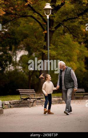 Beau grand-père passant du temps avec sa petite-fille dans le parc le jour de l'automne Banque D'Images