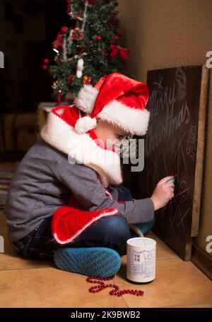 Moments d'enfance. Concept des fêtes de Noël. Garçon à côté de l'arbre de Noël à la maison. Joie et bonheur. Banque D'Images