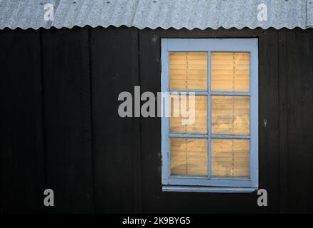 Fenêtre avec stores vénitiens dans Un Shack en bois peint au pas, Hengistbury UK Banque D'Images