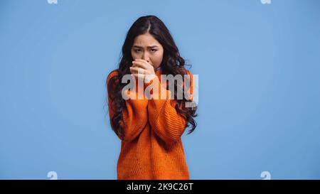 brunette et une jeune femme asiatique en chandail réchauffant les mains tout en se sentant au froid isolé sur le bleu Banque D'Images