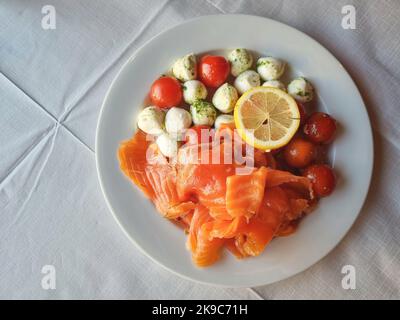 Saumon cru avec fromage mozzarella et tomates et tranche de citron vue de dessus Banque D'Images