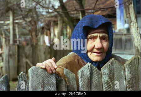 Comté de Gorj, Roumanie, environ 2000. Portrait d'une femme âgée locale à l'extérieur de sa clôture. Banque D'Images