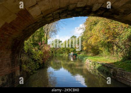 Couleurs d'automne sur le canal Kennet et Avon avec des bateaux étroits amarrés, vue depuis sous le pont Ladydown. Banque D'Images