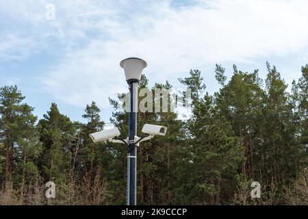 Caméras de surveillance montées sur un lampadaire sur le côté d'une route forestière. Caméra de vidéosurveillance de sécurité. Sécurité dans la ville. Le tournage caché de ce qui est happeni Banque D'Images