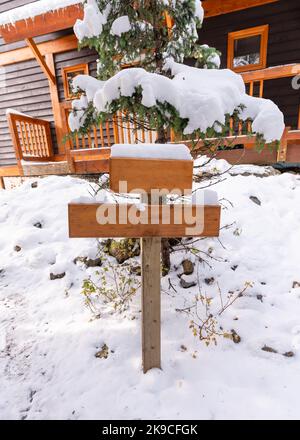 Poteau de panneau en bois recouvert de neige ou guide sur le devant de la maison en bois en hiver Banque D'Images