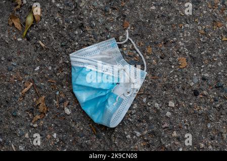 Utilisé masque chirurgical jeté sur la rue, symbole de pollution en temps de pandémie Banque D'Images