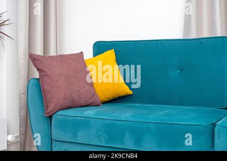 Oreiller jaune vif sur un canapé ou un canapé bleu turquoise, intérieur de la confortable chambre résidentielle Banque D'Images