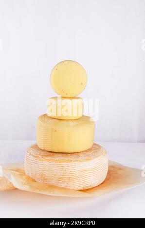 Pile de têtes de fromage de différents types empilées en ligne verticale sur la table. Têtes de fromage dures moyennes sur planche à découper en bois. Alimentation biologique saine conc Banque D'Images