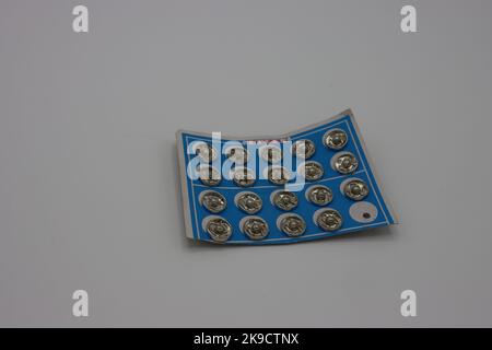 Accessoires de couture sur fond blanc. Enclenchez les fixations sur un porte-papier Banque D'Images