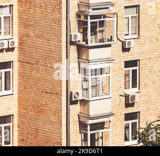 immeuble d'appartements en briques façade ensoleillée avec ses vitrages en plastique de fenêtres et balkomies, climatiseurs Banque D'Images