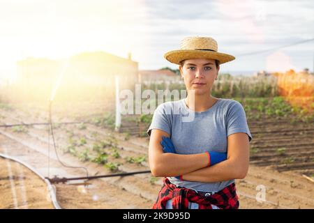 Jeune horticulteur femelle debout dans le champ agricole avec système d'irrigation Banque D'Images