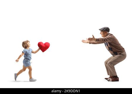 Photo pleine longueur d'une petite fille qui court vers un homme âgé et porte un cœur rouge isolé sur fond blanc Banque D'Images