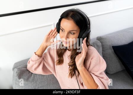 Femme écoutant de la musique avec un casque, se détendant à la maison Banque D'Images