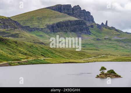 Le Storr, au-delà du loch, au loin, un important site de Skye, des visages abruptes de falaises déchiquetées, petite île de roche dépassant de l'eau, route de montagne ne Banque D'Images