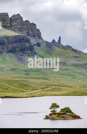 Le Storr, au-delà du loch, au loin, un important site de Skye, des visages abruptes de falaises déchiquetées, petite île de roche dépassant de l'eau, route de montagne ne Banque D'Images