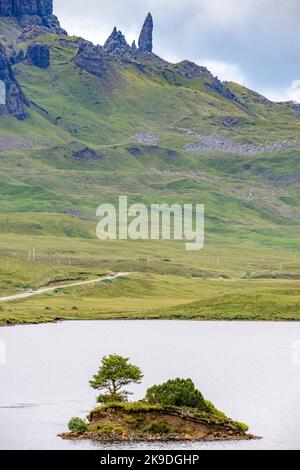 Le Storr, au-delà du loch, au loin, un important site de Skye, des visages abruptes de falaises déchiquetées, petite île de roche dépassant de l'eau, route de montagne ne Banque D'Images