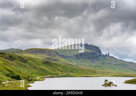 Le Storr, au-delà du loch, au loin, un important site de Skye, des visages abruptes de falaises déchiquetées, petite île de roche dépassant de l'eau, route de montagne ne Banque D'Images