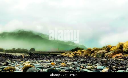 Pile de bois de grève et de billes lavées sur la plage couverte de rochers et de pierres Banque D'Images