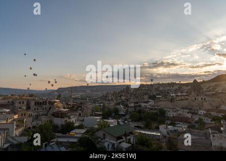 Montgolfières survolant les formations rocheuses uniques et la ville de Göreme à l'aube, Cappadoce, Turquie. Banque D'Images