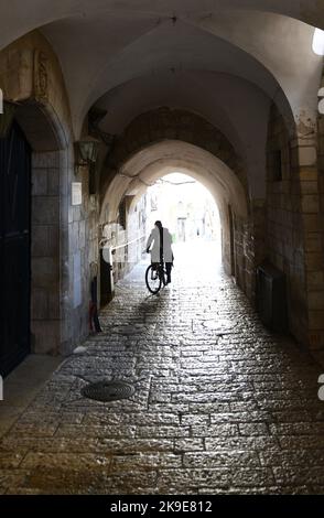 Un homme à vélo sur l'ancienne rue pavée du quartier chrétien de la vieille ville de Jérusalem, Israël. Banque D'Images