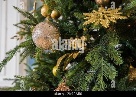 Arbre de Noël avec des glands vintage et des boules aux lumières dorées gros plan. Branches de sapin de noël à la décoration moderne avec ornements élégants de fête Banque D'Images