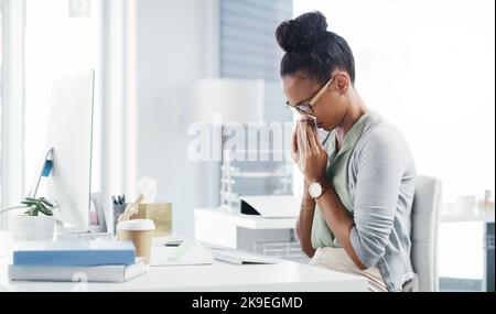 Je ne pense pas mal faire le reste de la journée. Une jeune femme d'affaires attirante soufflant son nez avec un mouchoir de papier lorsqu'elle est à son bureau dans un bureau moderne. Banque D'Images