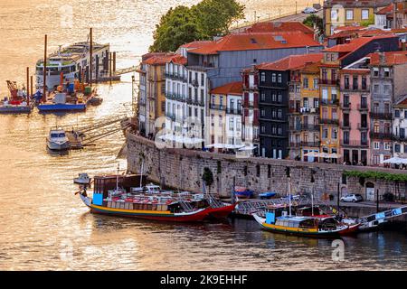 Façades de maisons traditionnelles portugaises colorées à Ribeira et bateaux rabelo amarrés à Douro à l'heure d'or du coucher du soleil, Porto, Portugal Banque D'Images