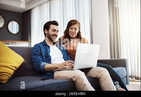 Je lui ai montré quelques astuces que j'ai apprises en ligne. Un jeune couple fait de la planification financière ensemble sur un ordinateur portable à la maison. Banque D'Images