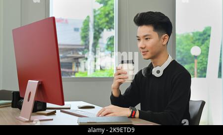 Homme créatif professionnel qui boit du café et travaille avec un ordinateur dans un studio de bureau à domicile Banque D'Images