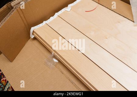 Vue depuis le dessus de la cloison verticale des bandes en bois d'un nouveau lit lors de déballage de déballage dans la salle de séjour Banque D'Images