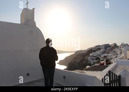 Garçon appréciant le coucher du soleil à Oia, Grèce , octobre 2022 Banque D'Images