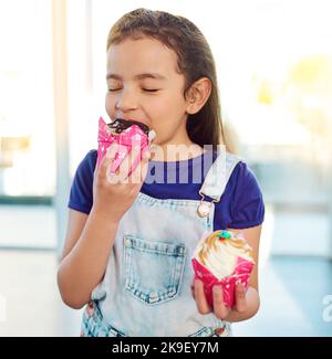 Vous pouvez voir le bonheur dans son visage. Une adorable petite fille mangeant un délicieux gâteau à la maison. Banque D'Images