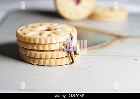 Miniature d'hommes et de biscuit montagne, une série de photographies utilisant des personnes miniatures, des biscuits à la confiture et des cailloux montrant un monde miniature d'images. Banque D'Images