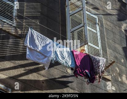 MARSEILLE, FRANCE, 9 JUILLET 2015 : une femme avec foulard fixe le linge sur une ligne de lavage devant la façade de marseille, France. Marseille a un Banque D'Images