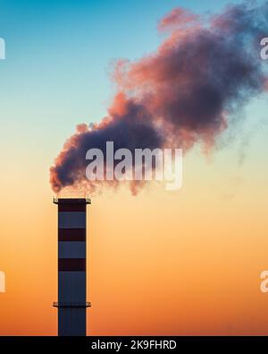 Cheminée de la chaufferie avec de la fumée qui en sort sur le fond du ciel. Banque D'Images