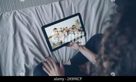 La fille sombre-cheveux parle avec des amis en ligne en utilisant la tablette regardant l'affichage, gestante et la main de signe. Technologie moderne, chat avec des amis et concept de la génération du millénaire heureuse. Banque D'Images