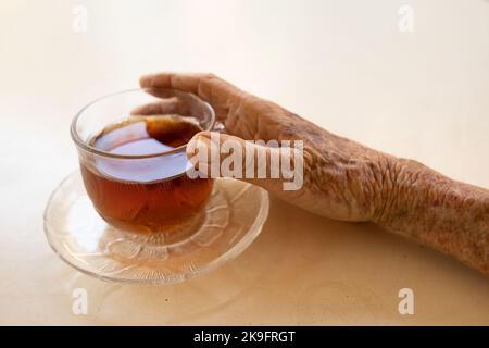 mains d'une femme âgée tenant une tasse de thé Banque D'Images