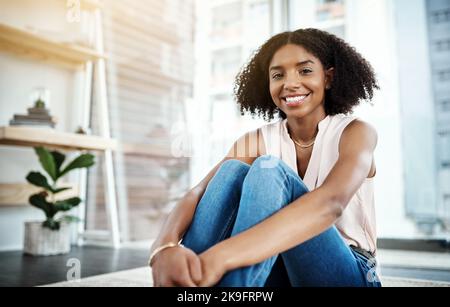 Se détendre à la maison ce week-end. Portrait court d'une jeune femme attrayante assise sur le sol à la maison. Banque D'Images