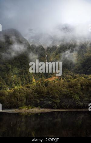 Une scène magique dans le Doubtful Sound alors que la lumière du soleil se brise à travers les nuages qui illuminent la forêt tropicale luxuriante de Nouvelle-Zélande. Banque D'Images