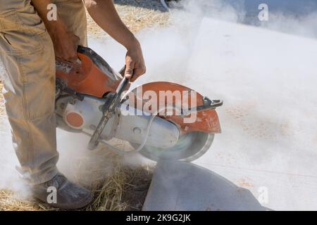 Travailleur de la construction coupant des pavés de béton pour trottoir à l'aide d'une scie à lame de diamant coupée. Banque D'Images