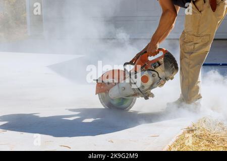 Découpe de dalles de béton à l'aide d'une scie à lame de diamant de la société de construction afin de poser les trottoirs. Banque D'Images