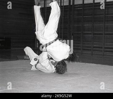 1970s, historique, à l'intérieur, sur un tapis, deux mâles en compétition dans le sport du judo, une activité physique qui implique deux personnes luttant et essayant de se jeter à la terre le judo est un mot japonais signifiant "art de la douceur" et dérive de l'art martial japonais antique du jujitsu. Banque D'Images