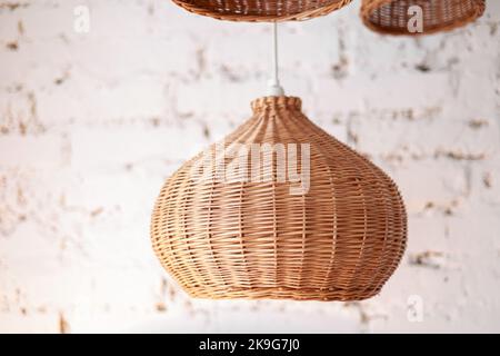 trois chandeliers en rotin différentes formes sur fond de mur en brique blanche. Abat-jour en paille dans le salon confortable. Design intérieur écologique utilisant des matériaux naturels. Intérieur scandinave. Espace de copie. Banque D'Images