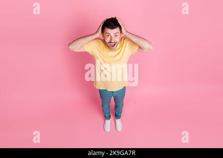 Photo pleine grandeur de l'homme optimiste impressionné avec la coupe de cheveux élégante porter t-shirt jaune paumes sur la tête yell isolé sur fond rose Banque D'Images