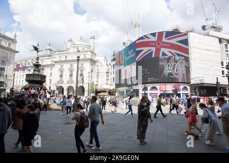 Les gens marchent devant un drapeau de l'Union avec un logo sur un tableau électrique à Piccadilly Circus, Londres, le premier jour du week-end du jubilé de platine. Banque D'Images